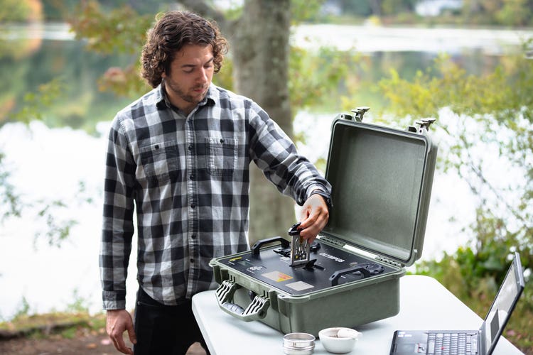 Prüfer mit TERRA XRD-Analysator, der eine aufbereitete Probe zur Analyse vor Ort in die Probenkammer einführt.