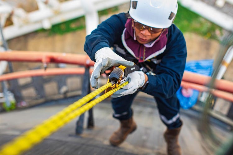 Worker scaling a tank using rope access inspection method to perform thickness testing