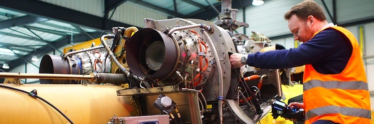 Aircraft maintenance technician performing a remote visual inspection of a helicopter rotor motor using an Olympus G Lite video