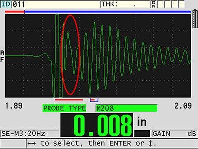 The trailing edge of the large interface echo interfering with the first back wall echo