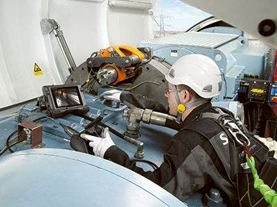 Up-tower inspector performing a borescope inspection of the interior of a gearbox in a wind turbine using a portable videoscope.