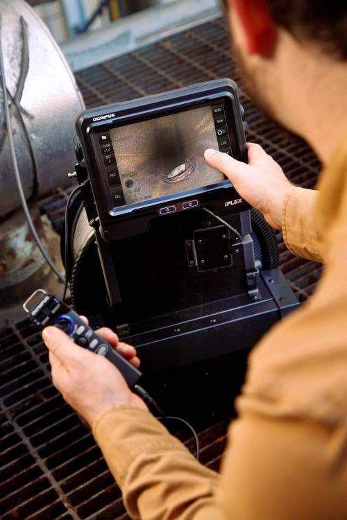 Inspector de soldaduras con un videoscopio Olympus IPLEX y una solución de alcance de 30 metros de largo inspeccionando el interior de una tubería de procesamiento con el mando liviano para controlar el tubo de inserción.