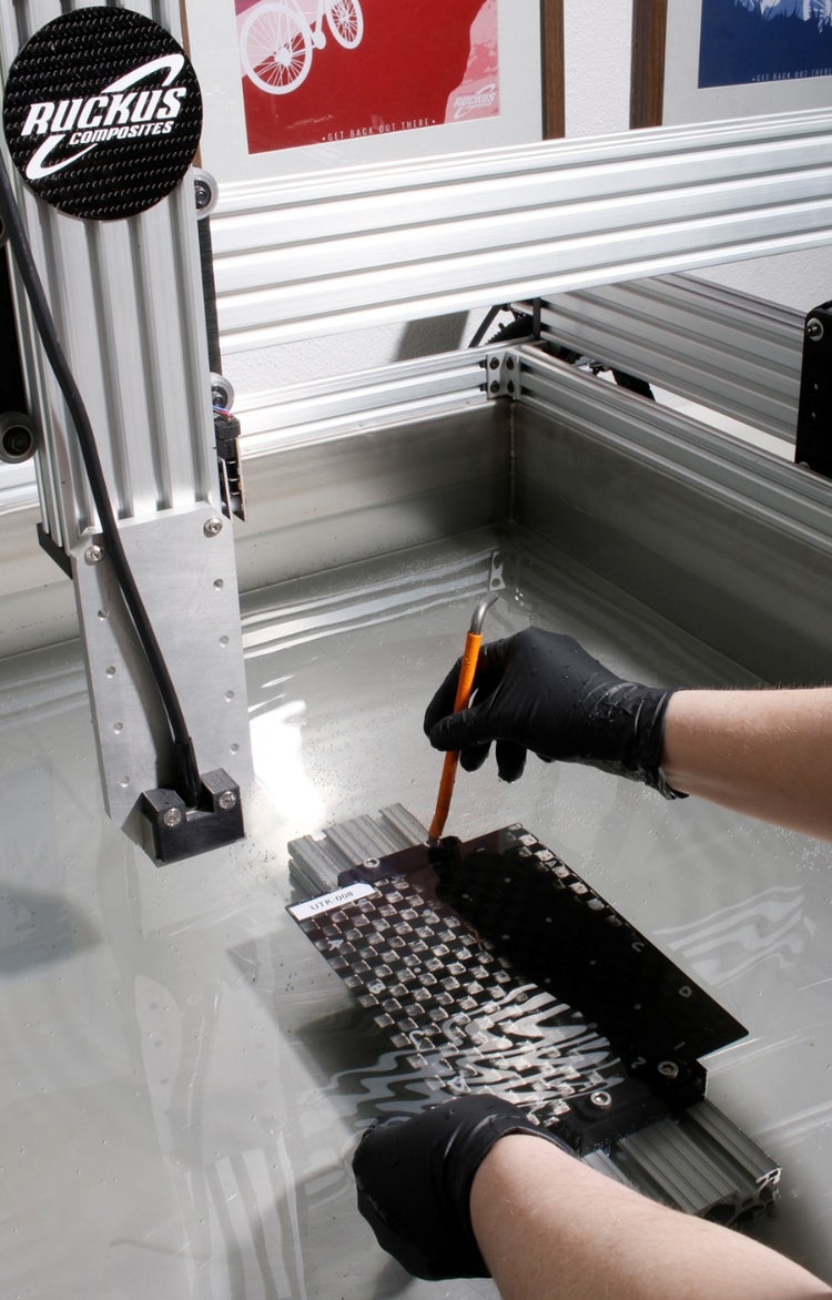 A person using a tool to fix a piece of metal Description automatically generated