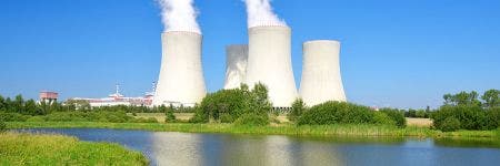 Centrale nucleare in lontananza con fiume in primo piano