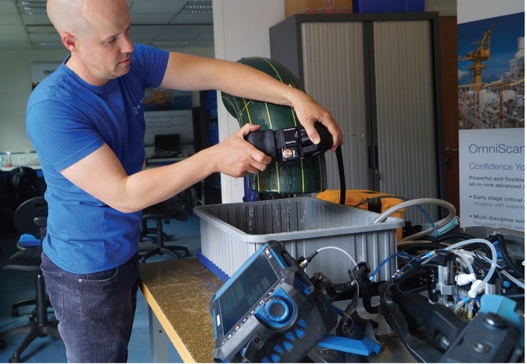 Ingegnere ISP di Mistras mentre utilizza lo scanner FlexoFORM su un campione di raccordo di tubazione con il rilevatore di difetti phased array OmniScan X3