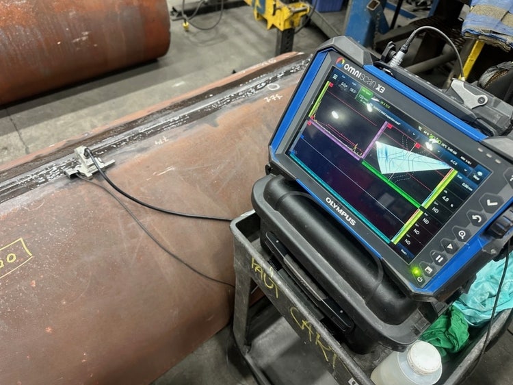 A12 probe and OmniScan flaw detector being used to inspect a weld in a metal pipe.