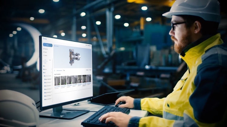 ViSOL工作流Inspector wearing hardhat and a yellow jacket in a factory looking at a computer screen displaying images of a remote visual inspection inside a component on ViSOL software